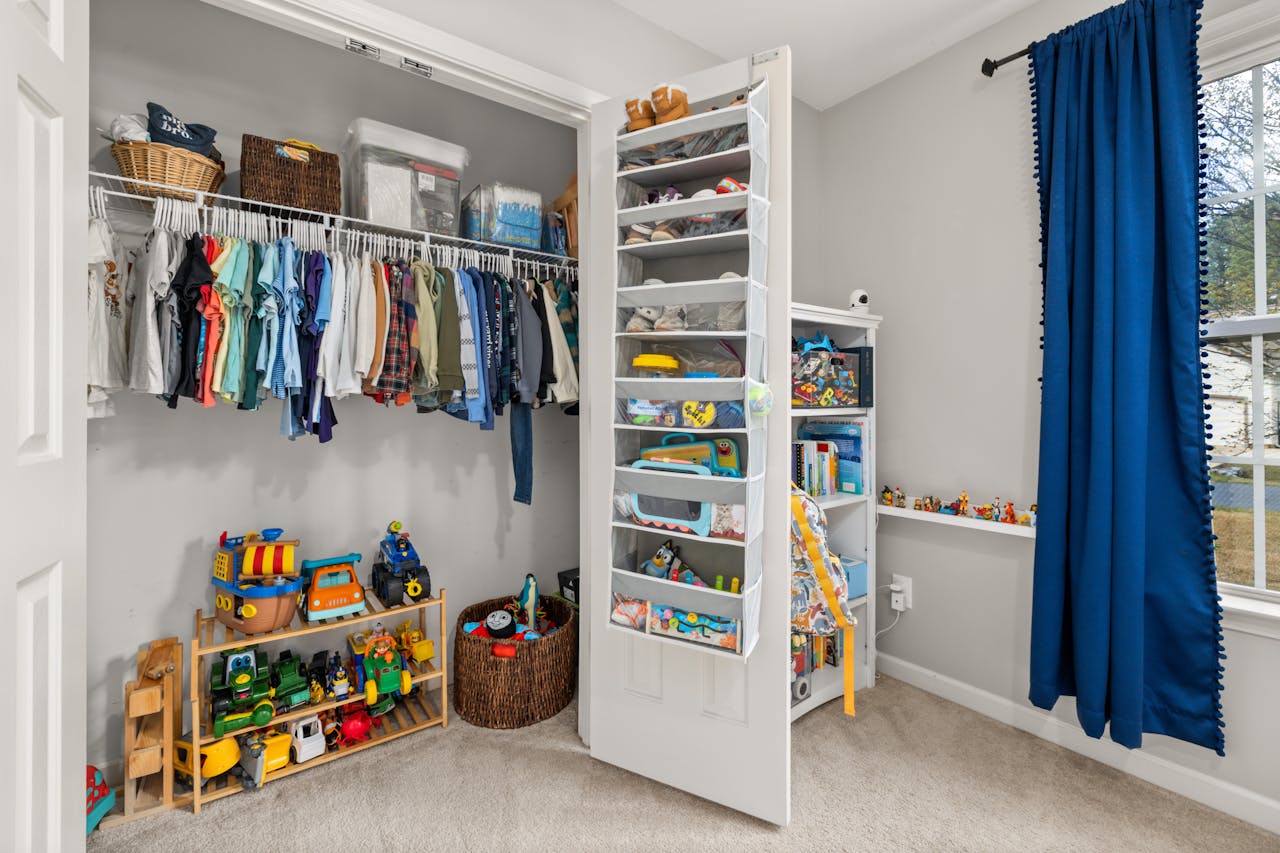 A neatly organized childrens closet featuring clothes, toys, and storage solutions.